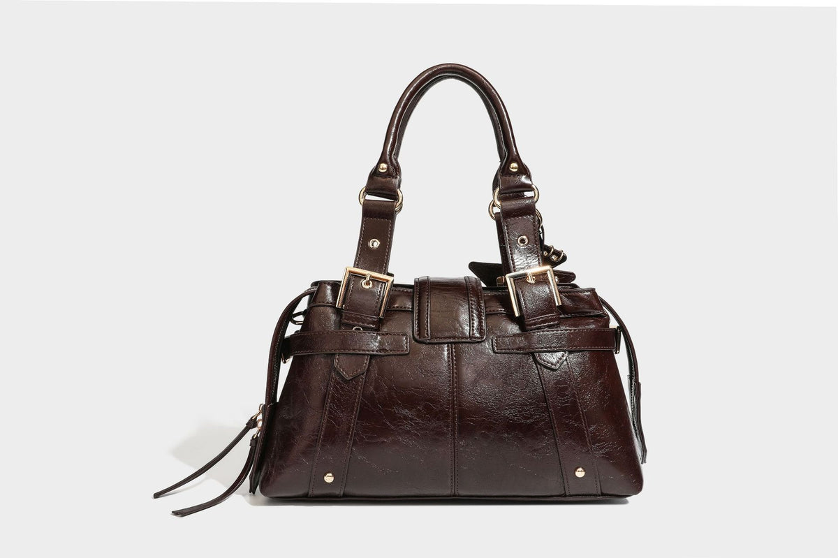 Structured leather-look satchel bag with heart padlock charm, star charm, gold-tone buckle hardware, dual top handles, and