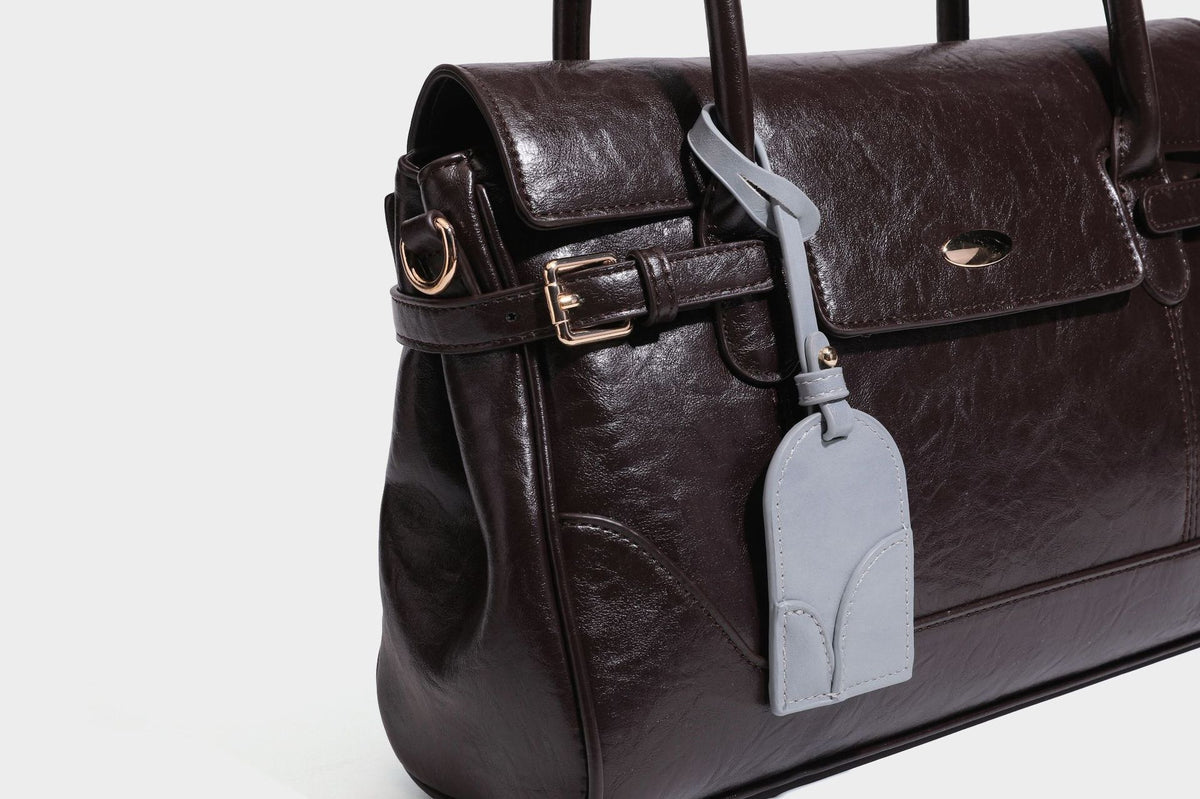 Structured glossy leather-look satchel bag with flap closure, gold-tone buckle accents, double top handles, detachable