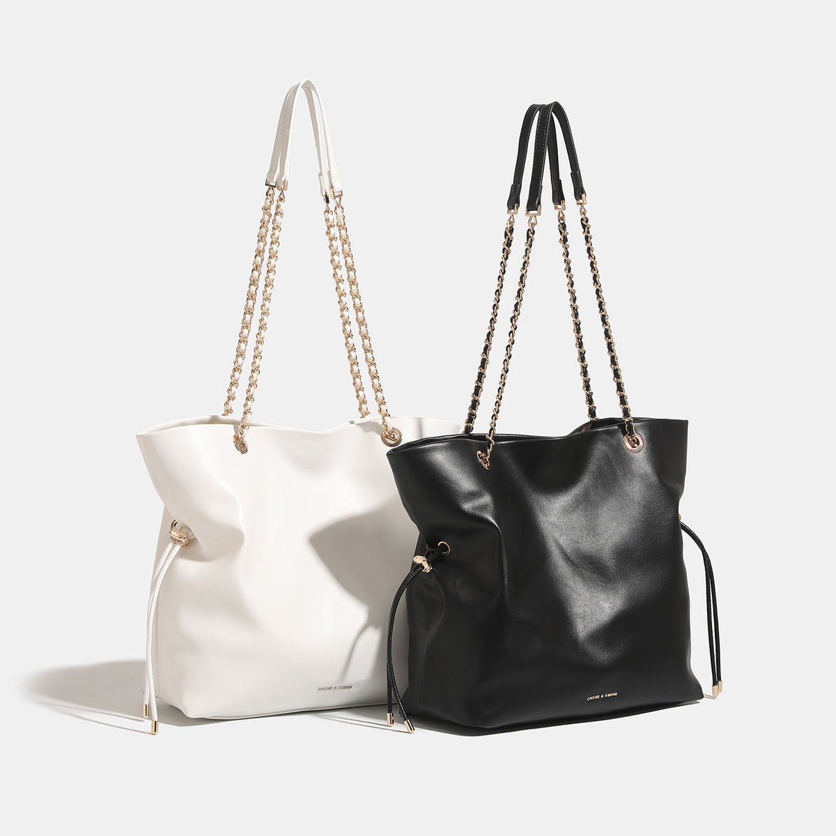 Soft-structured leather-look tote bag with gold-tone chain-and-strap shoulder handles and side drawstring cinches, detail