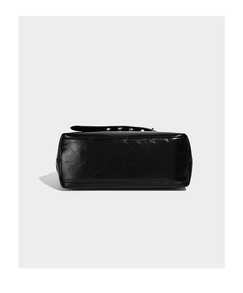 Glossy black slouchy hobo shoulder bag with silver-tone hardware, belt-style grommet strap at base, and long adjustable