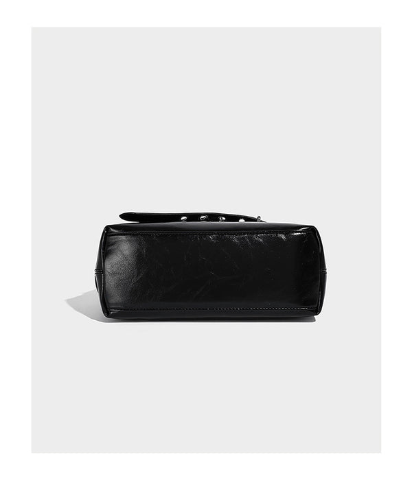 Glossy black slouchy hobo shoulder bag with silver-tone hardware, belt-style grommet strap at base, and long adjustable
