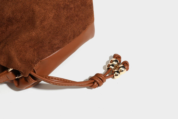 Suede-look drawstring shoulder bag in brown with smooth trim, knotted bead drawstring closure, slim adjustable strap, and