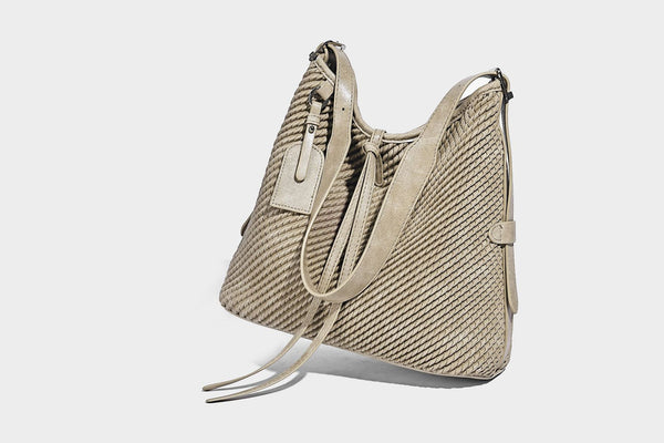 Große Schultertasche im Beuteltaschenstil mit Flechtstruktur, glatten Besätzen in Lederoptik, verstellbarem Riemen und Anhänger-Detail, Detailansicht