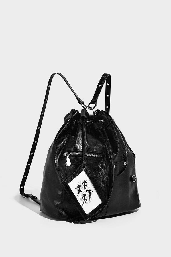 Glossy black convertible bucket backpack with silver grommet-studded straps, drawstring cinch closure, and front zip pocket