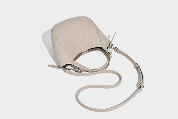 Small pebbled half-moon shoulder bag with dual top handles, detachable crossbody strap, and silver-tone hardware, detail view
