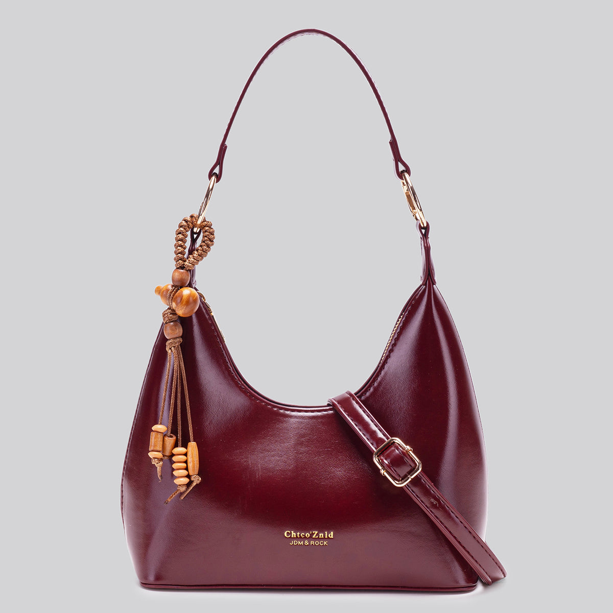 Glossy crescent hobo shoulder bag in deep burgundy with beaded wood tassel charm and gold-tone ring hardware, front view