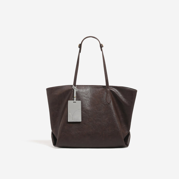 Oversized slouchy leather-look tote bag with long shoulder straps, contrast grey hanging tag, and silver-tone hardware