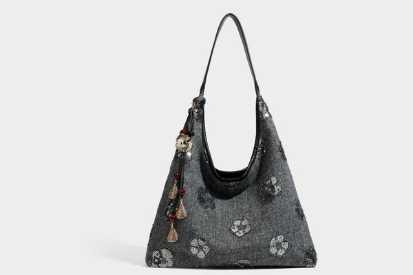 Lässig fallende, trapezförmige Schulter-Tote in Anthrazitgrau mit floralen Paillettenmotiven in Silber, Riemen in Lederoptik und herabhängendem Perlenbesatz