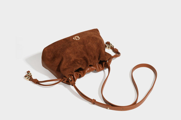 Suede-look drawstring shoulder bag in brown with smooth trim, knotted bead drawstring closure, slim adjustable strap, and