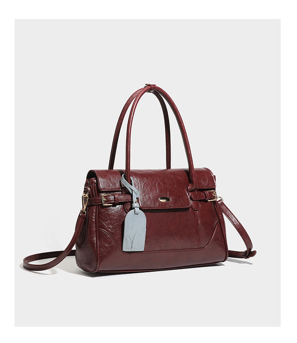 Structured glossy leather-look satchel bag with flap closure, gold-tone buckle accents, double top handles, detachable