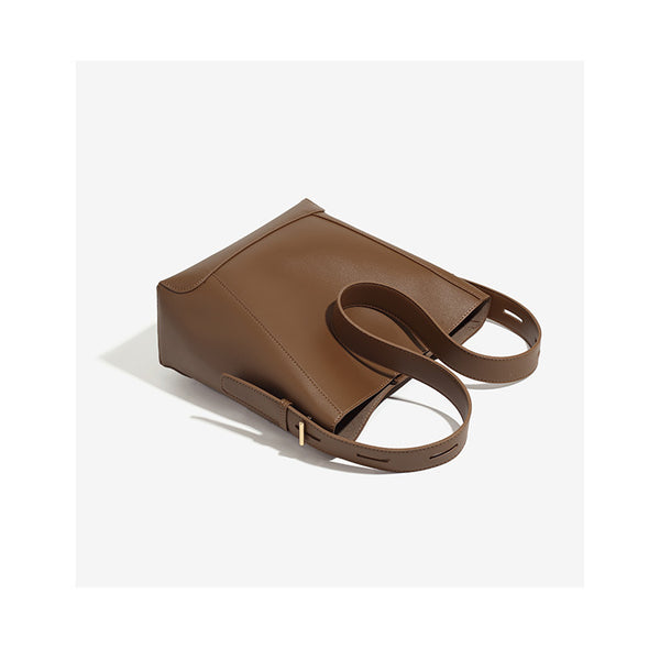 Structured smooth leather-look bucket shoulder bag with long adjustable strap and gold-tone buckle hardware in brown, detail