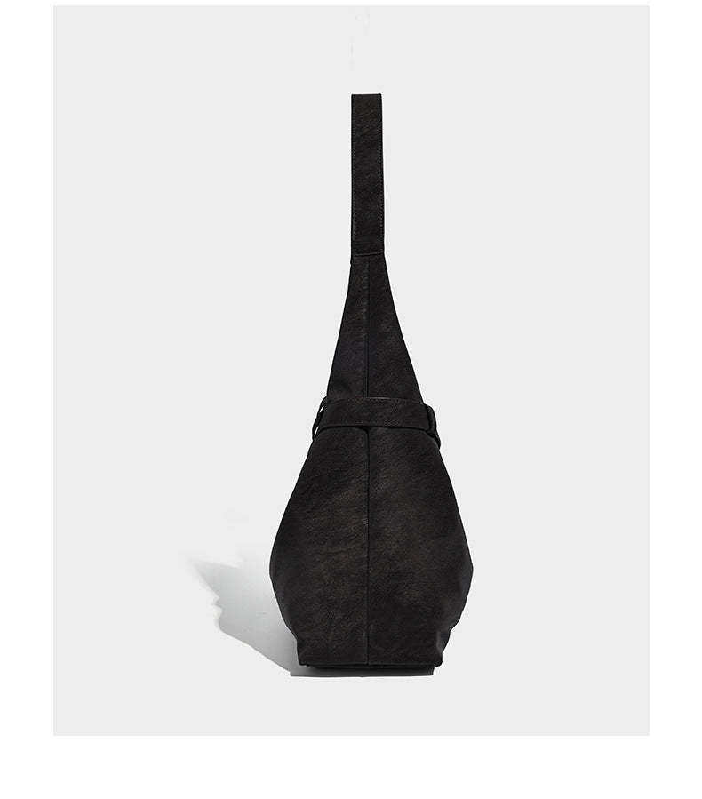 Slouchy oversized shoulder tote bag with matte textured finish, wrap-around buckle strap, and detachable front zip pouch