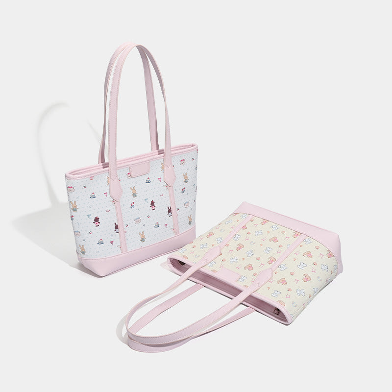 Large structured zip-top tote bag with pastel cartoon print panels and smooth pink leather-look trim, dual shoulder straps