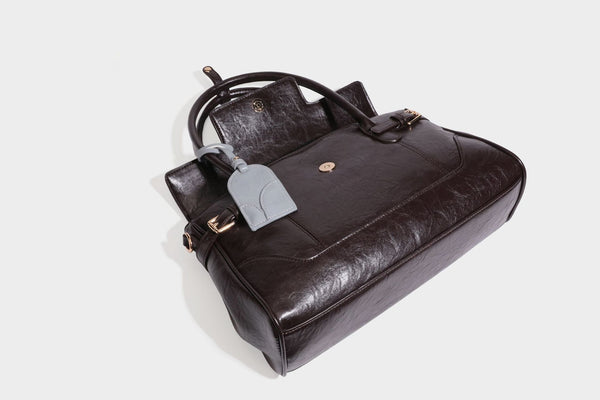 Structured glossy leather-look satchel bag with flap closure, gold-tone buckle accents, double top handles, detachable
