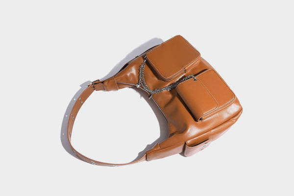 Lässig fallende Hobo-Schultertasche mit glänzender Lederoptik, vorderen Klappentaschen, Kettenapplikationen und silberfarbenen Nietbeschlägen