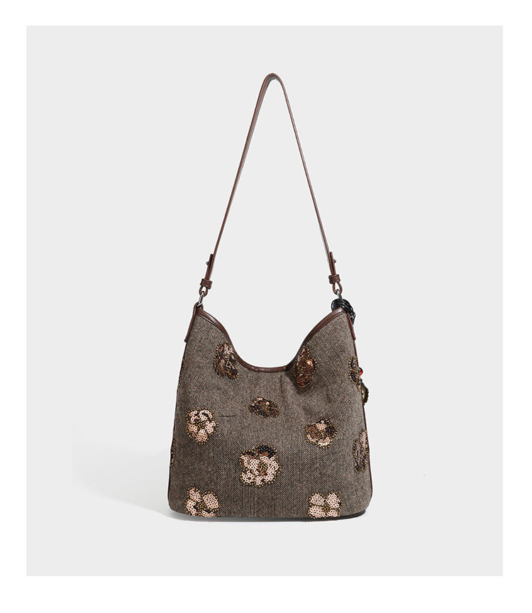 Lässig fallende Hobo-Schultertasche aus anthrazitfarbenem Webstoff mit floraler Stickerei aus silberfarbenen Pailletten, schwarzem Besatz in Lederoptik und langem