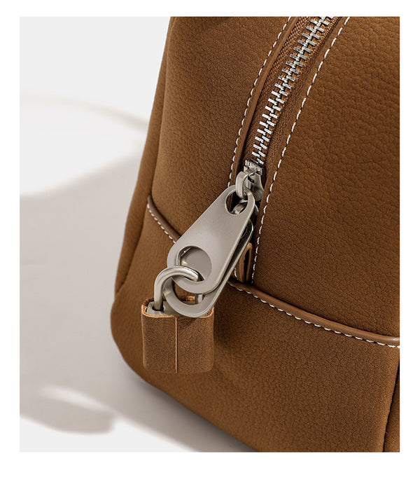 Kompakte, strukturierte Henkeltasche mit matter genarbter Oberfläche, geknoteten Doppelhenkeln, goldenem Schlüsselanhänger und abnehmbarem, Detail