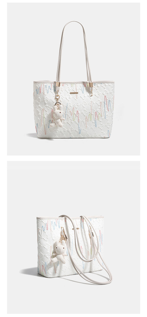 Off-white structured tote bag with dual shoulder straps, gold-tone hardware, and plush bear charm, detail view 10