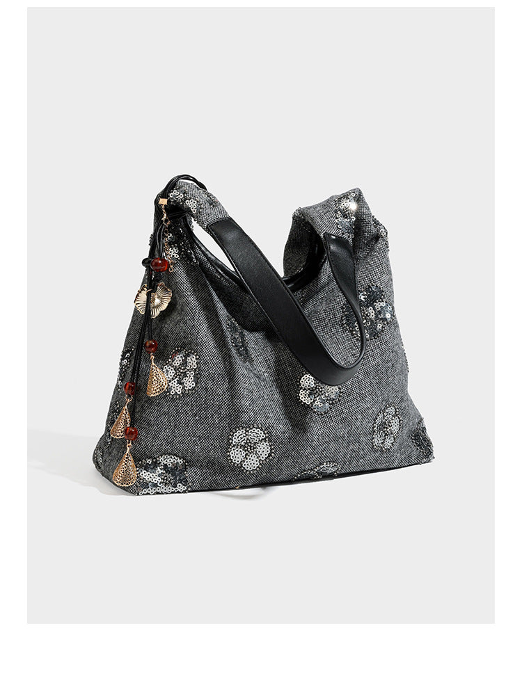 Lässig fallende, trapezförmige Schulter-Tote in Anthrazitgrau mit floralen Paillettenmotiven in Silber, Riemen in Lederoptik und herabhängendem Perlenbesatz