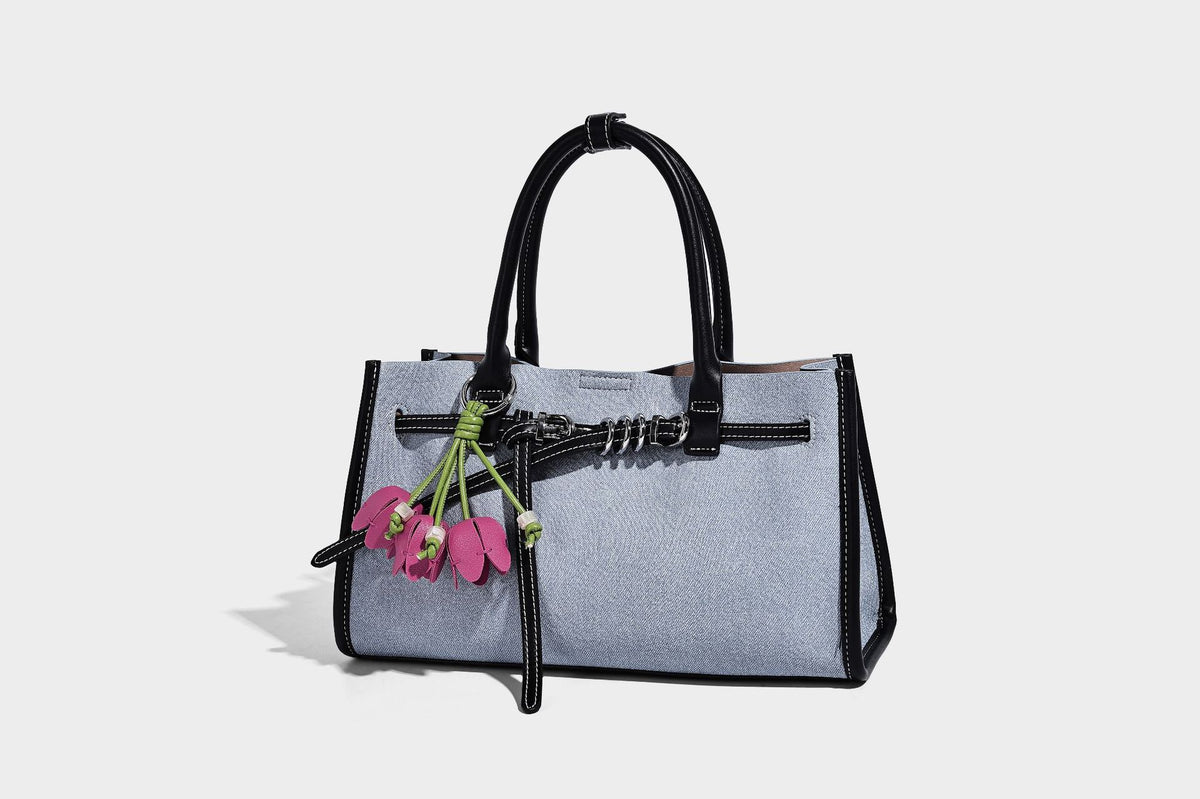 Structured rectangular tote satchel in denim-look fabric with dark trim, knotted front strap hardware, and detachable, detail