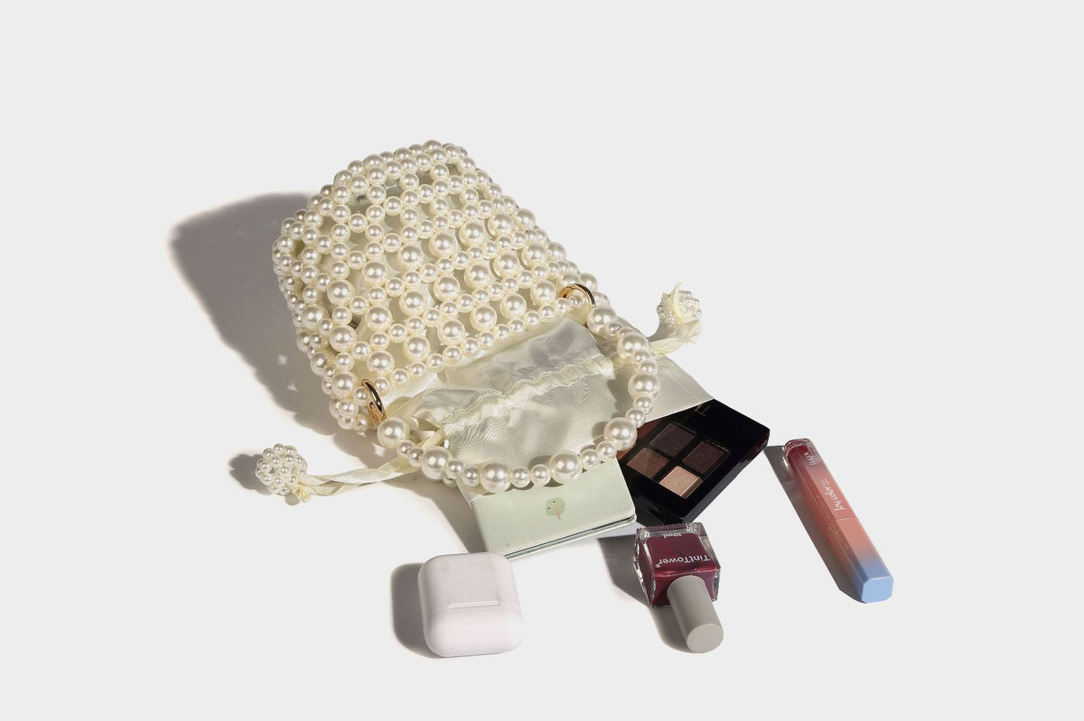 Elfenbeinfarbene Mini-Bucket-Bag aus Kunstperlen mit Satin-Innenbereich und Zugband, goldfarbenen Ringbeschlägen und gewölbtem Perlenhenkel an der Oberseite