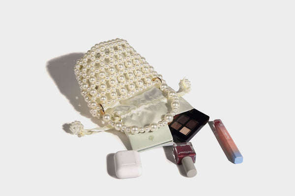 Elfenbeinfarbene Mini-Bucket-Bag aus Kunstperlen mit Satin-Innenbereich und Zugband, goldfarbenen Ringbeschlägen und gewölbtem Perlenhenkel an der Oberseite