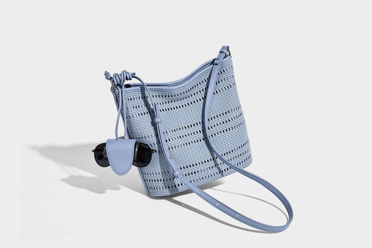 Handwoven open-weave shoulder bag with leather-look trim, knotted adjustable strap, and clip-on sunglasses sleeve pouch