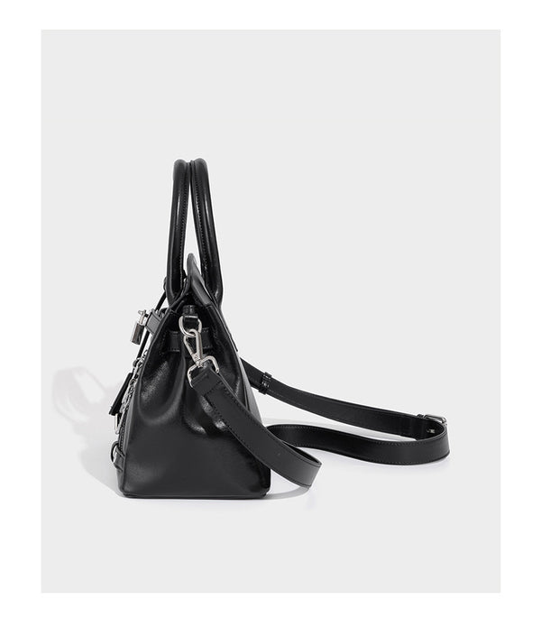 Structured black leather-look satchel bag with silver padlock hardware, front zip pockets, key charms, and top handles