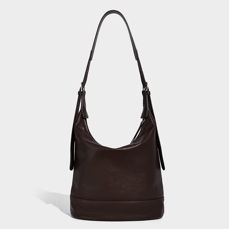 Slouchy bucket hobo shoulder bag in dark brown with glossy leather-look finish, top zip closure, and long adjustable, detail