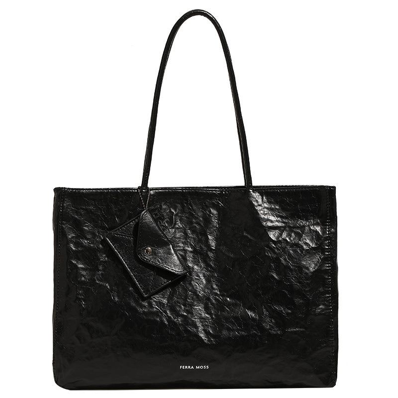 Large glossy crinkled rectangular tote bag with long double handles and hanging envelope snap tag, detail view 5