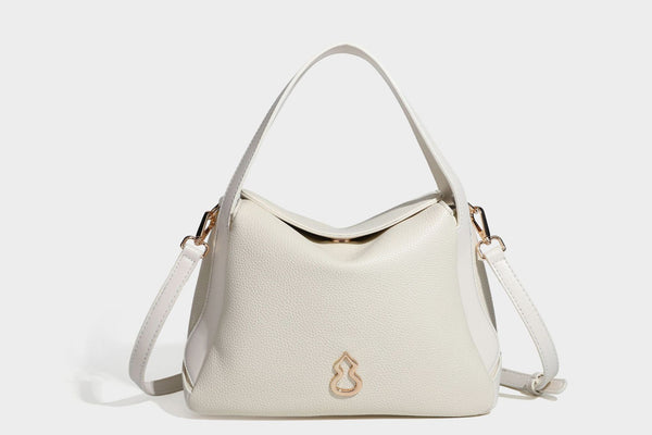 Structured pebbled leather-look shoulder bag with flap top, gold-tone emblem hardware, dual top handles, and detachable