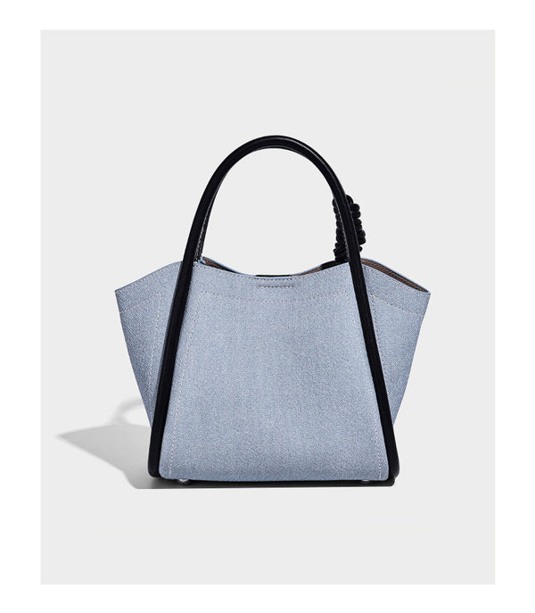 Structured canvas tote bag with knotted top handles, leather-look black trim, front flap pocket, and pink tulip flower charm
