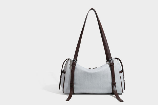 Olivgrüne Canvas-Schultertasche in Zylinderform mit schwarzen Trägern in Lederoptik, Reißverschluss oben und silberfarbenen Metallbeschlägen, Detailansicht