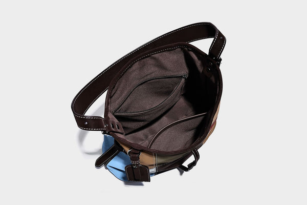 Patchwork bucket tote shoulder bag with tan, dark brown, olive, red, and sky blue color-block panels, white contrast, detail