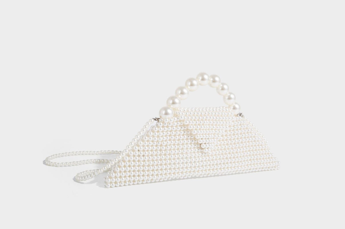 Small structured triangle clutch bag covered in glossy pearl beads with an arched pearl top handle and silver snap closure