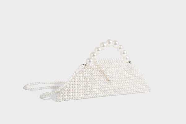 Small structured triangle clutch bag covered in glossy pearl beads with an arched pearl top handle and silver snap closure