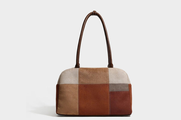 Boxy patchwork suede-look shoulder tote in tan, beige, rust, and brown panels with double brown straps and hanging doll