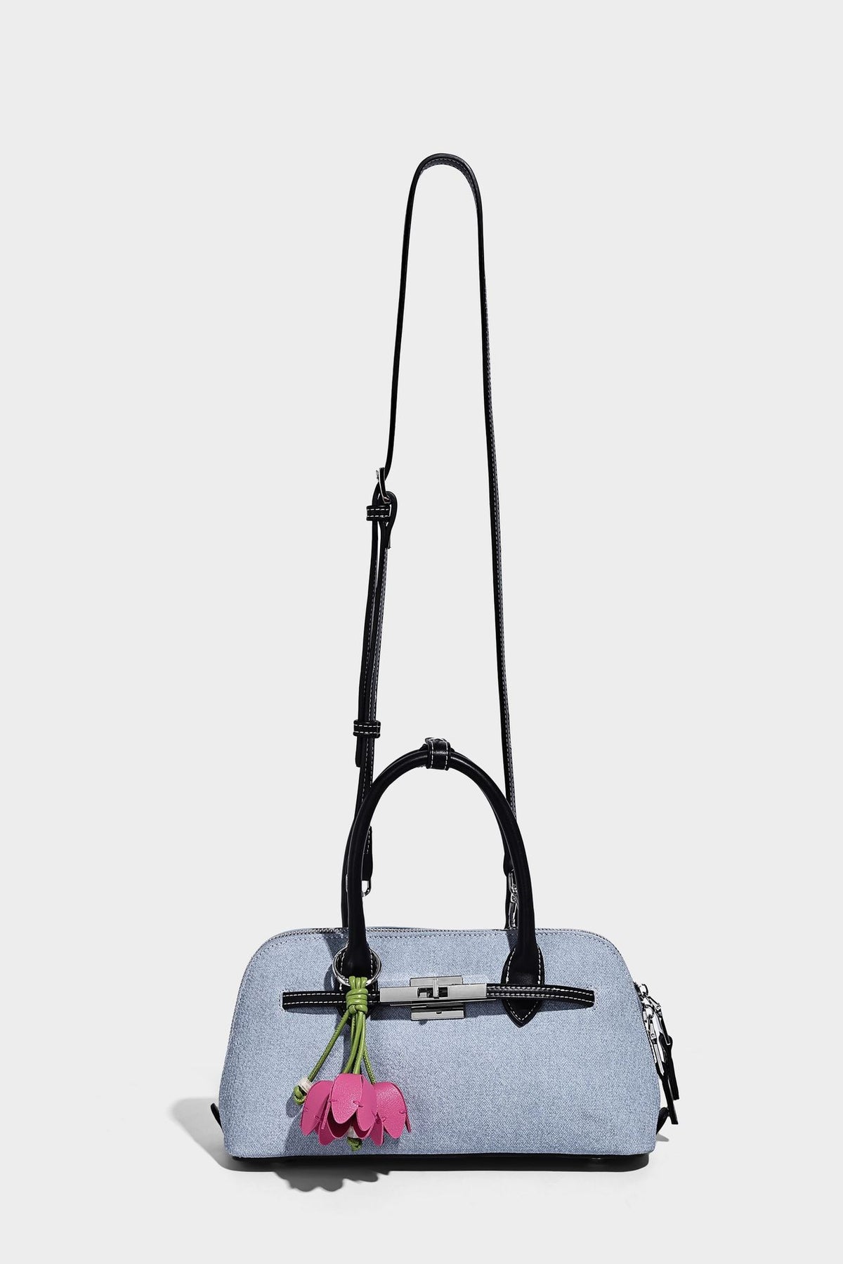 Compact structured satchel in light blue denim-look fabric with black leather-look trim, silver turn-lock closure, rolled
