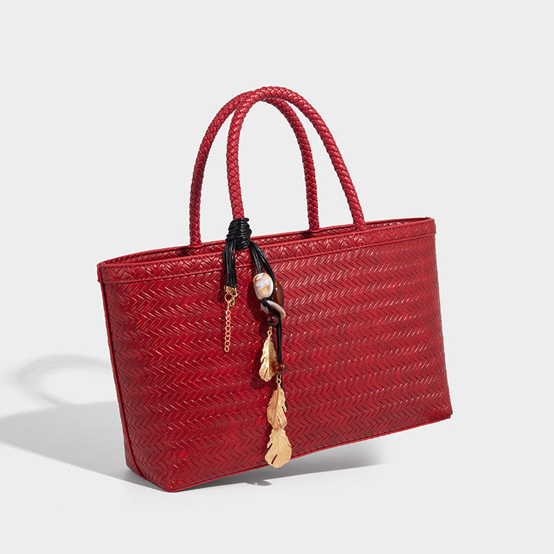 Structured woven-texture tote bag with brown braided top handles, decorative tassel charm, and detachable shoulder strap