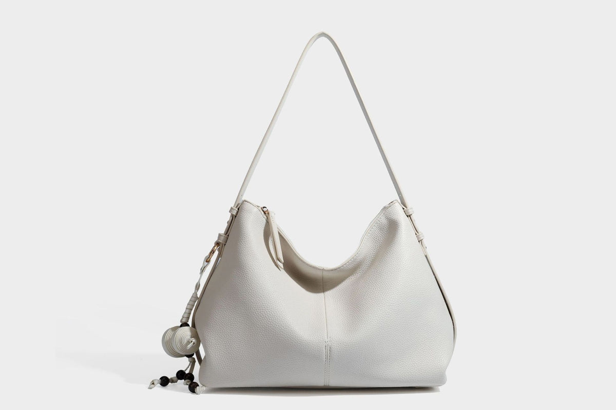 Slouchy hobo shoulder bag with pebbled leather-look finish, zip-top closure, gold-tone hardware, and hanging bead charm
