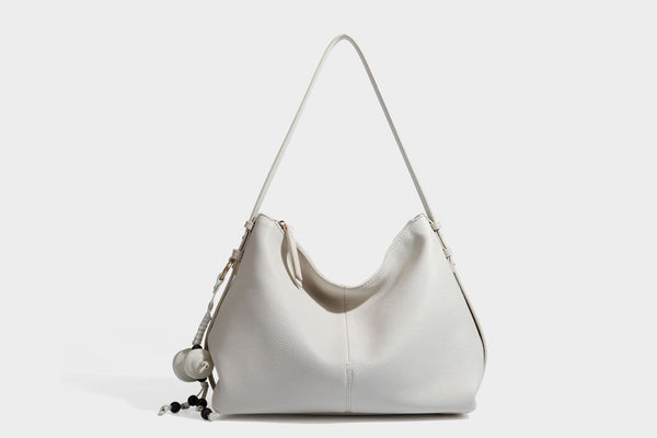 Slouchy hobo shoulder bag with pebbled leather-look finish, zip-top closure, gold-tone hardware, and hanging bead charm