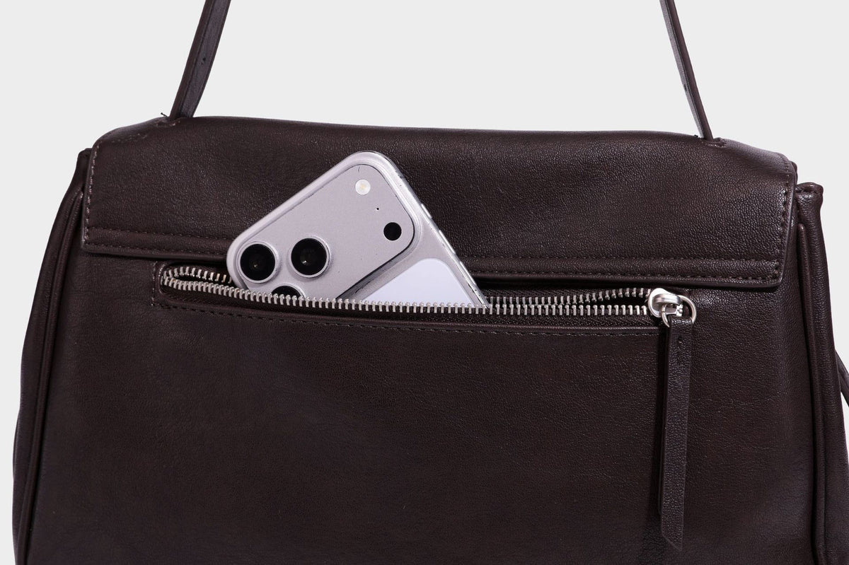 Strukturierte rechteckige dunkelbraune Schultertasche in Lederoptik mit Klappe, mehrlagigem Detail auf der Vorderseite und langem verstellbarem Riemen, Detailansicht
