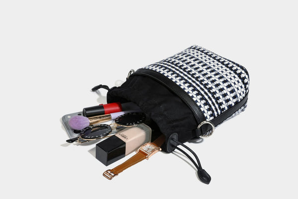 Small structured woven checker bucket bag with braided top handle, drawstring closure, and silver-tone hardware in black