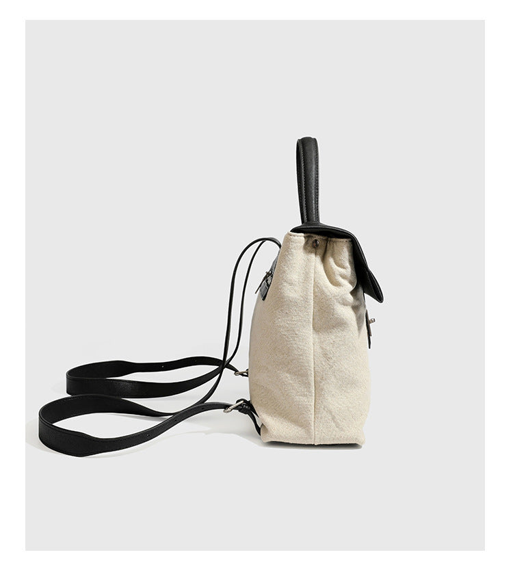 Strukturierter beigefarbener Rucksack aus gewebtem Canvas mit schwarzer Klappe in Lederoptik, Drehverschluss, Tragegriff und flachem Schulter