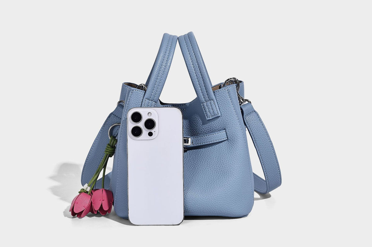 Small structured pebbled bucket tote bag with dual top handles, silver turn-lock front pocket, and detachable shoulder strap