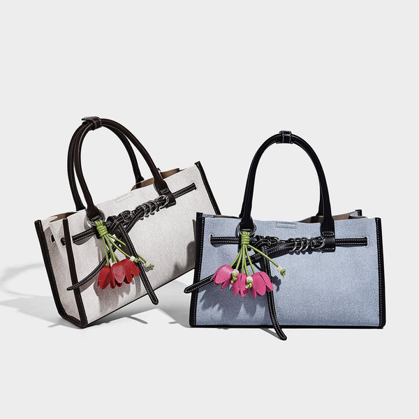 Structured rectangular tote satchel in denim-look fabric with dark trim, knotted front strap hardware, and detachable, detail