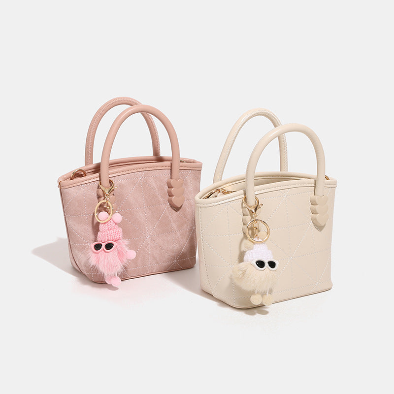 Quilted leather-look mini bucket tote bag with heart-shaped side accents, gold-tone hardware, fuzzy character charm, and