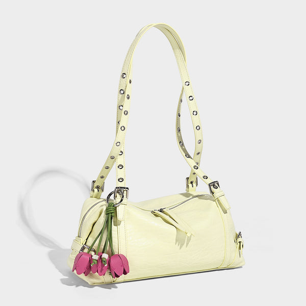 Pale yellow leather-look barrel bag with silver grommet-studded shoulder straps, top zip closure, and pink tulip floral