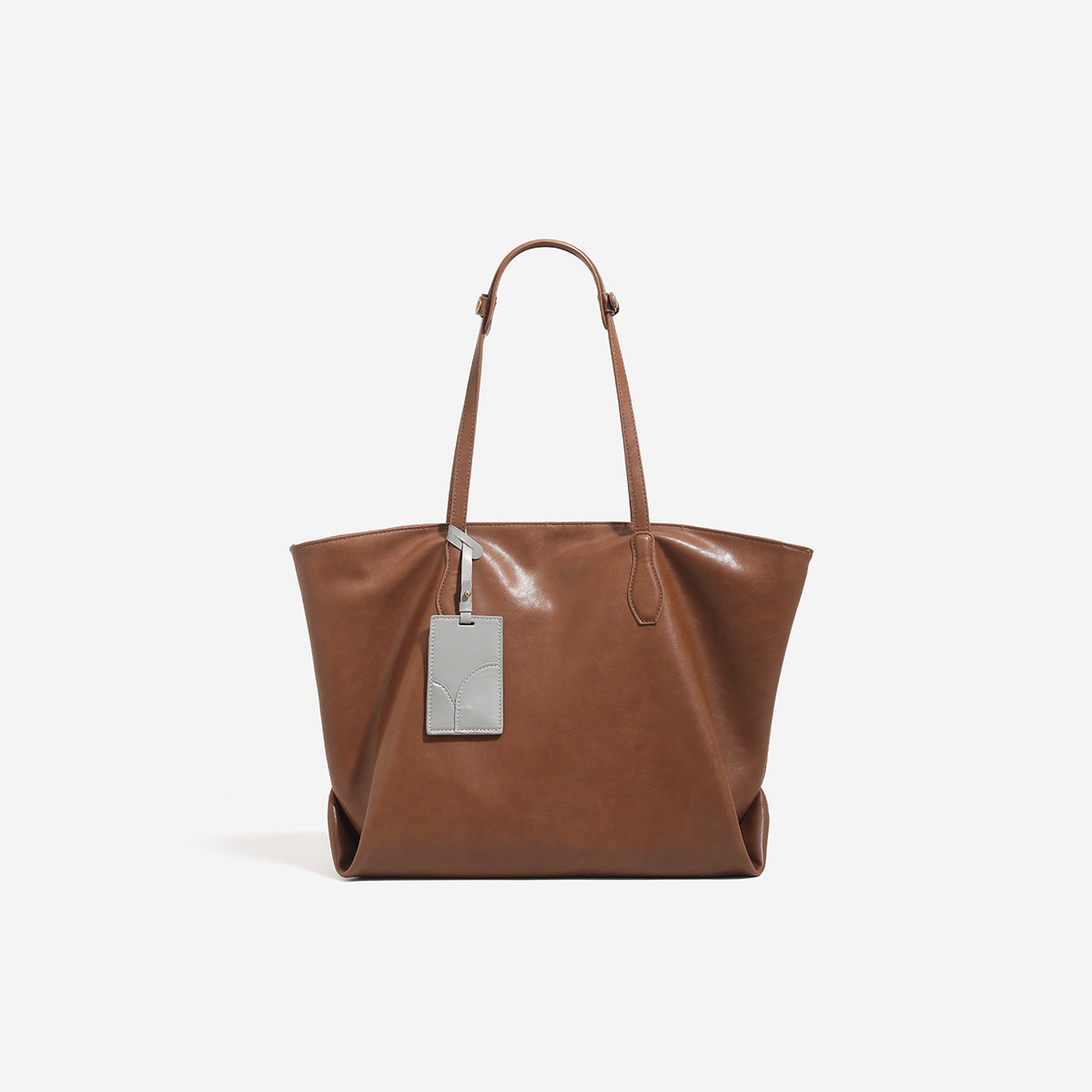 Oversized slouchy leather-look tote bag with long shoulder straps, contrast grey hanging tag, and silver-tone hardware