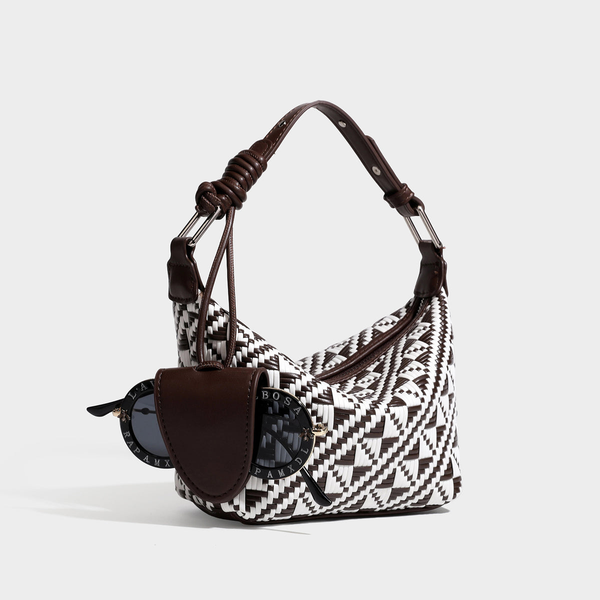 Kleine gewebte Schultertasche mit geometrischem Schwarz-Weiß-Muster, glatten dunkelbraunen Details in Lederoptik, geknotetem verstellbarem Riemen, Seitenansicht